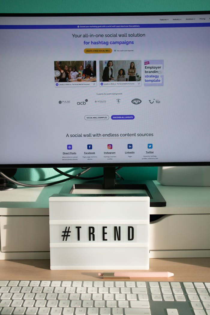 services-04 A clean and modern desk setup with a lightbox displaying '#TREND' and a computer monitor showing a social wall solution.
