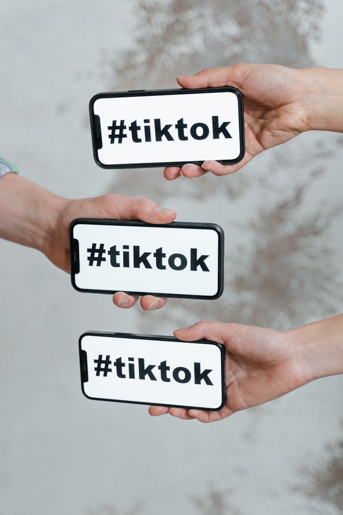 Hands holding smartphones displaying TikTok hashtag, emphasizing social media connection.